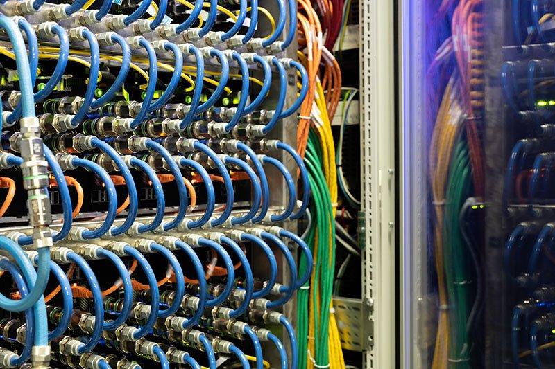 Close-up of modern supercomputer equipment with optic cables and hubs in server room, copy space